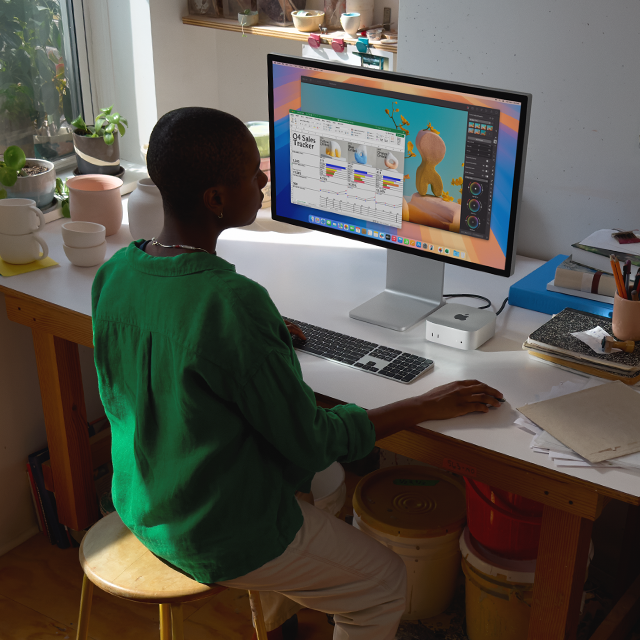 Una persona usa una Mac mini conectada a un monitor para trabajar en apps con una pantalla colorida